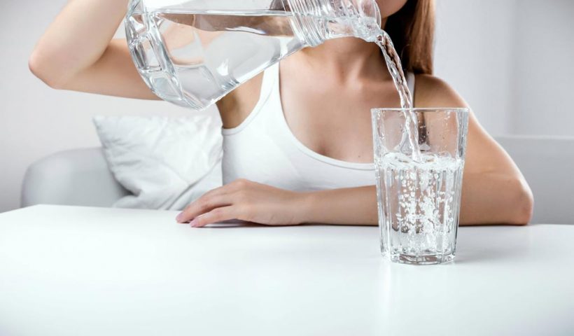 Девушка наливает воду из кувшина в стакан
